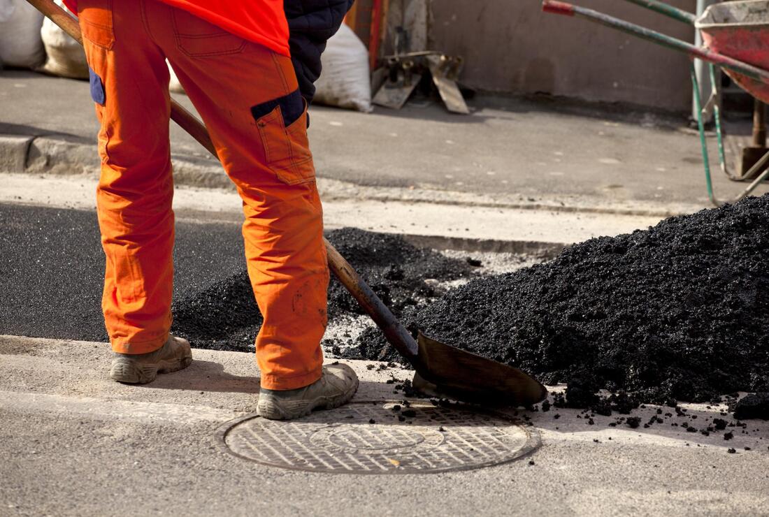 worker shoveling the asphalt