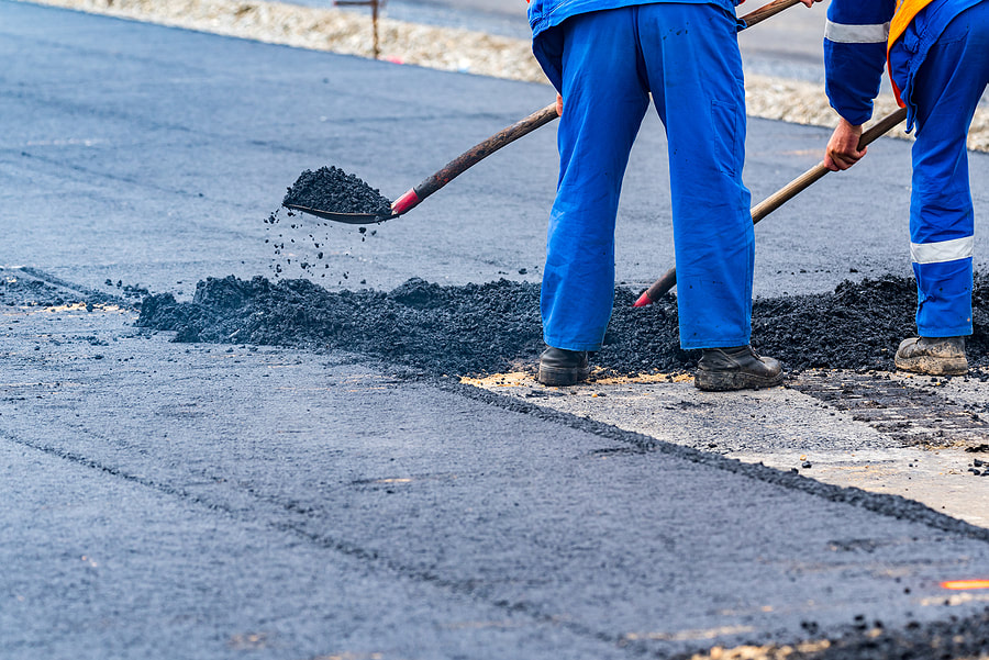 workers are shoveling the asphalt